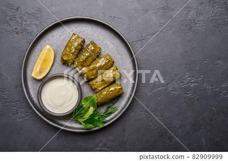 Homemade Middle Eastern dish dolma or sarma, with parsley, saucepan with sour cream and lemon Homemade Middle Eastern dish dolma or sarma, with parsley, saucepan with sour cream and lemon 82909999
