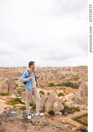 Tourist man outdoor on edge of cliff seashore Tourist man outdoor on edge of cliff seashore 82910014
