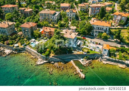 Beautiful villas near the coast of rocky beach in a small town Lovran, Croatia. Arial view of Lungomare sea walkway with transparent water. Beautiful villas near the coast of rocky beach in a small town Lovran, Croatia. Arial view of Lungomare sea walkway with transparent water. 82910218