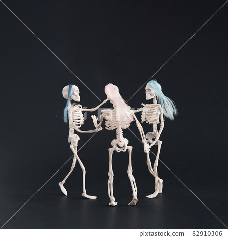 Three skeletons like three graces dancing on a black background. 82910306