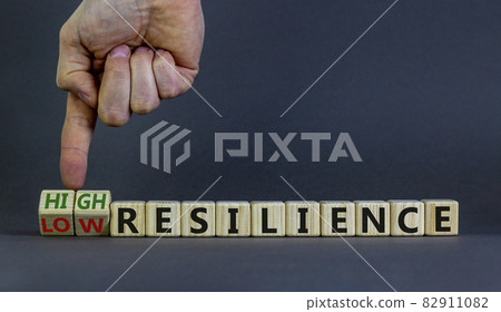 High or low resilience symbol. Businessman hand turns cubes and changes words 'low resilience' to 'high resilience'. Business and high resilience concept. Beautiful grey background, copy space. 82911082