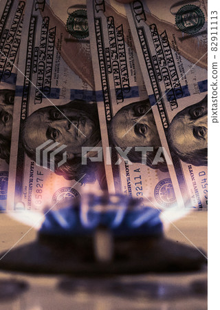 Burning gas stove burner and US dollar banknotes. Pay for natural gas, gas bill, tariff. Pile of coins and burning fire gas stove hob and money Burning gas stove burner and US dollar banknotes. Pay for natural gas, gas bill, tariff. Pile of coins and burning fire gas stove hob and money 82911113