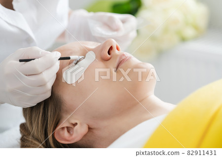 Cosmetician giving eyelash treatment to customer Cosmetician giving eyelash treatment to customer 82911431
