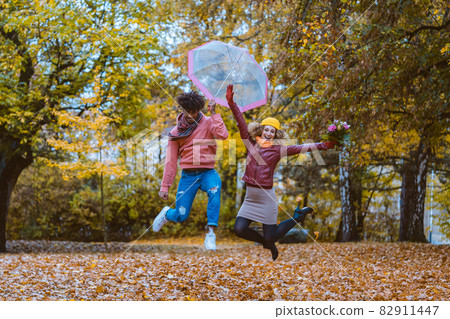 Man and woman jumping joyfully in the autumn park Man and woman jumping joyfully in the autumn park 82911447