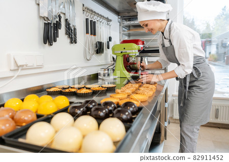 Confectioner working on lots of different sweets and desserts 82911452