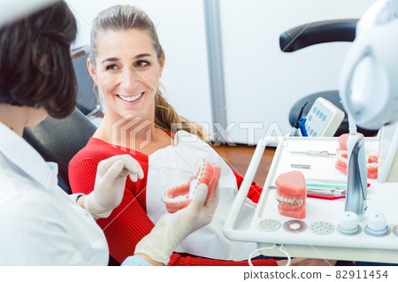 Dentist explaining to patient about dentures 82911454