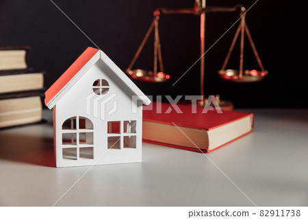 Sale of real property concept. Wooden model of house and law book 82911738
