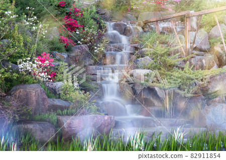 Smooth flowing water falling over many plants in the rocks in korean park 82911854