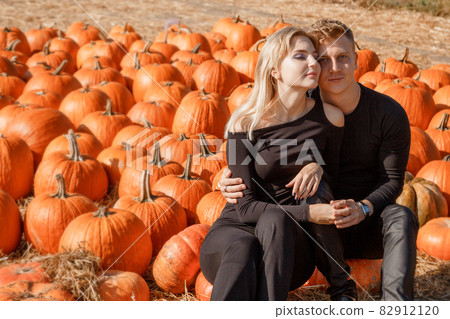 Couple sitting in field near pumpkin, concept halloween. Young couple near pumpkin, autumn time. 82912120