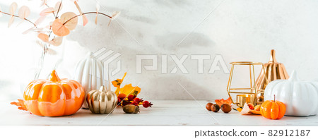 Details of Still life, cup of tea or coffee, pumpkins, candle, brunch with leaves on white table background, home decor in a cozy house. Autumn weekend concept. Fallen leaves and home decoration. Details of Still life, cup of tea or coffee, pumpkins, candle, brunch with leaves on white table background, home decor in a cozy house. Autumn weekend concept. Fallen leaves and home decoration. 82912187