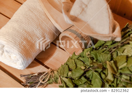 Traditional old Russian bathhouse SPA Concept. Interior details Finnish sauna steam room with traditional sauna accessories set towel birch broom scoop felt. Relax country village bath concept. 82912362