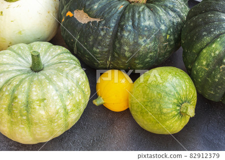 Autumnal Background. Natural autumn fall view pumpkins on dark black stone shale background, October or september wallpaper Change of seasons ripe organic food concept Halloween party Thanksgiving day 82912379
