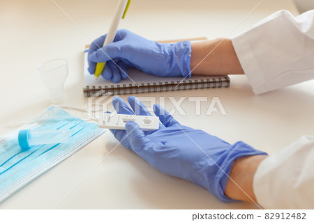 sars covid antigen test. doctor hands in blue gloves holding rapid test and writing results to note 82912482