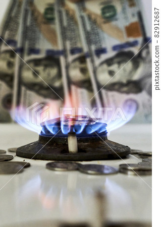 Burning gas stove burner and US dollar banknotes. Pay for natural gas, gas bill, tariff. Pile of coins and burning fire gas stove hob and money 82912687