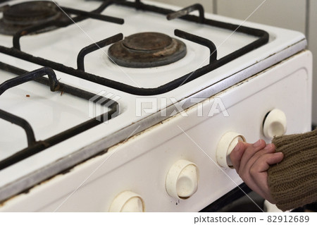 Woman checking gas. Female hand trying to turn on old gas stove. No gas, Winter and cold period concepts. Lack of gas in the pipeline 82912689