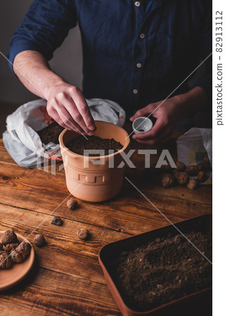 Man Sowing Thyme Seeds into Terracotta Pot 82913112