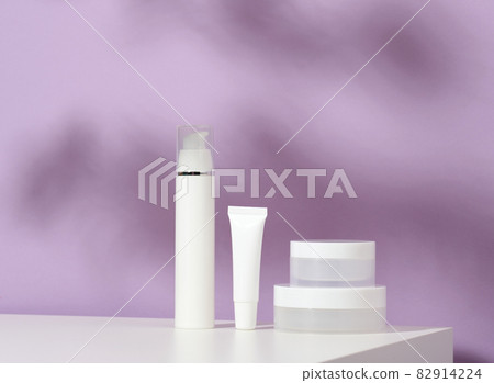 jar and empty white plastic tubes for cosmetics on a purple background. Packaging for cream, gel, serum, advertising and product promotion, mock up jar and empty white plastic tubes for cosmetics on a purple background. Packaging for cream, gel, serum, advertising and product promotion, mock up 82914224