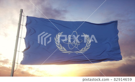 Flag of International Atomic Energy Agency IAEA waving in the wind, sky and sun background. 3d rendering Flag of International Atomic Energy Agency IAEA waving in the wind, sky and sun background. 3d rendering 82914659