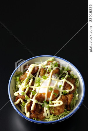 A bird's-eye view of shredded cabbage, all-purpose onions, hot spring eggs, and karaage bowl on a black background 82916826
