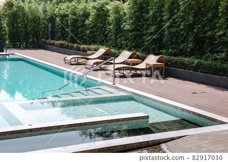 Swimming Pool Ladder and Sun Lounger in Poolside, Luxury Outdoor Swim Pool and Modern Decoration of Resort Hotel. Relaxation Swimming Pool in Summer Holiday and Leisure Vacation Lifestyles. 82917030