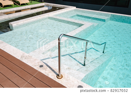 Swimming Pool Ladder and Sun Lounger in Poolside, Luxury Outdoor Swim Pool and Modern Decoration of Resort Hotel. Relaxation Swimming Pool in Summer Holiday and Leisure Vacation Lifestyles. 82917032