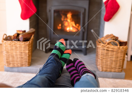 Feet of couple wearing christmas socks and resting on sofa close to fireplace at christmas time 82918346