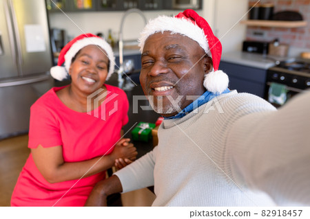 Happy african american senior couple taking selfie in kitchen at christmas time Happy african american senior couple taking selfie in kitchen at christmas time 82918457