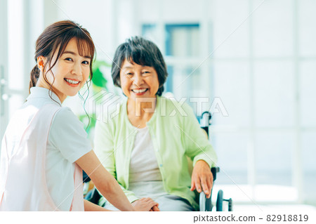 Elderly and young care workers in wheelchairs 82918819