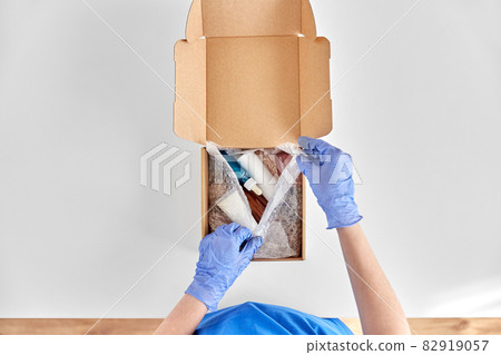 hands in gloves packing parcel box with cosmetics 82919057