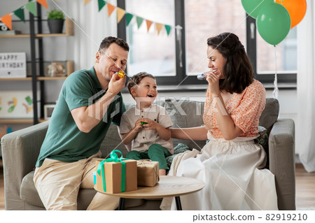 happy family with gifts and party blowers at home 82919210
