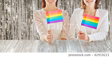 close up of happy lesbian couple with rainbow flag 82919221