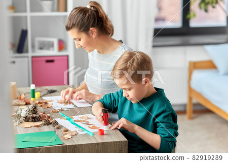 mother and son making pictures of autumn leaves 82919289