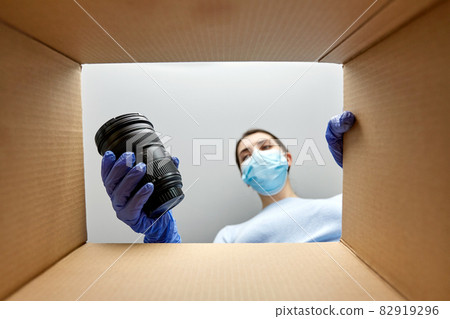 woman in mask packing camera into parcel box 82919296