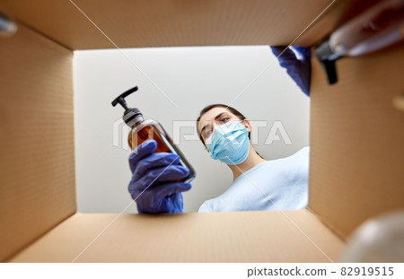 woman in mask unpacking parcel box with cosmetics 82919515