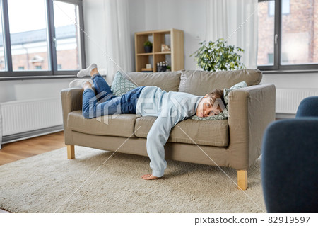 bored or lazy young man lying on sofa at home 82919597