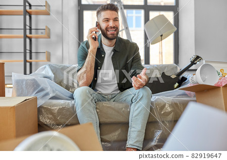 happy man calling on smartphone moving to new home happy man calling on smartphone moving to new home 82919647