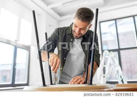 happy man assembling coffee table at new home happy man assembling coffee table at new home 82919681