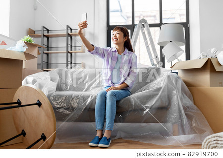 woman with phone having video call at new home woman with phone having video call at new home 82919700