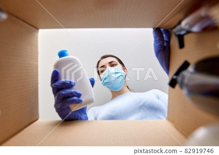 woman in mask unpacking parcel box with cosmetics 82919746