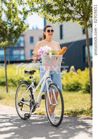 woman with food and flowers in bicycle basket 82919851