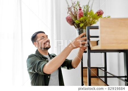 man decorating home with flowers in vase 82919884