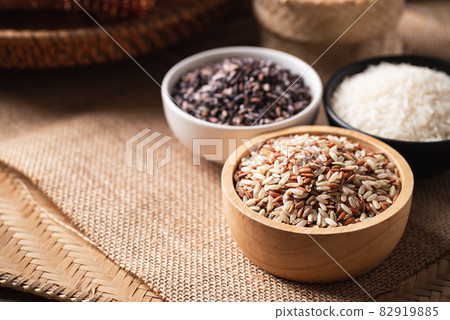 Various Organic Thai rice grain (brown, purple and white rice) in a bowl on brown background 82919885