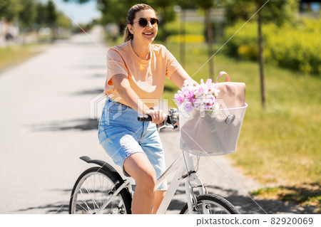 woman with flowers in bicycle basket in city woman with flowers in bicycle basket in city 82920069