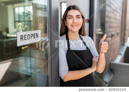 woman with reopen banner on door showing thumbs up 82920124