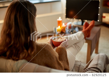 woman watches tv and drinks cocoa on halloween 82920125