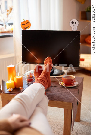 young woman watching tv at home on halloween 82920174