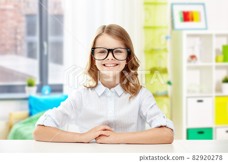 smiling student girl in glasses sitting at table smiling student girl in glasses sitting at table 82920278