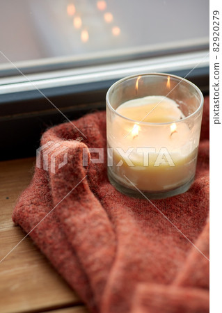 woolen sweater and candle burning on window sill woolen sweater and candle burning on window sill 82920279