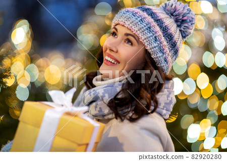 happy woman with christmas gift over lights happy woman with christmas gift over lights 82920280