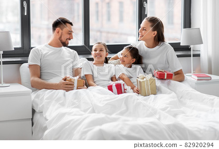 happy family with christmas gifts in bed at home 82920294
